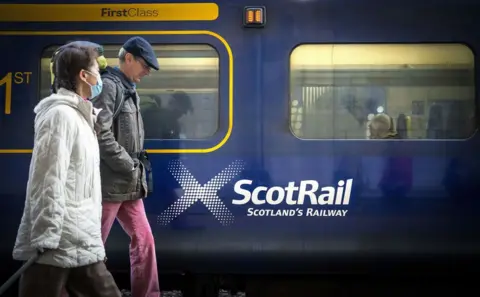 PA Media scotrail train passengers beside a train 