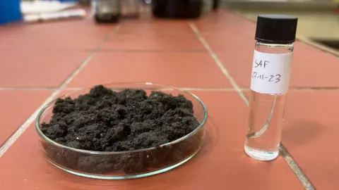 A petri dish of human waste next to a bottle of sustainable aviation fuel. 