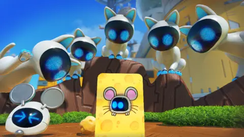 Team Asobi Five white, robotic cats with black screens for faces train their bright blue LED eyes on a board decorated to look like a piece of cheese with a mouse in the middle. A smaller robot peeks through a hole in the middle of the board, his blue eyes looking nervously to the side.