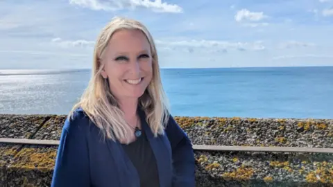 Jennifer McKiernan/ BBC Dr Roz Savage by the seafront at the Liberal Democrat autumn conference in Brighton. She has loose, shoulder-length blonde hair, black eye make-up and a royal blue cardigan with a black t-shirt underneath and a round, blue necklace.