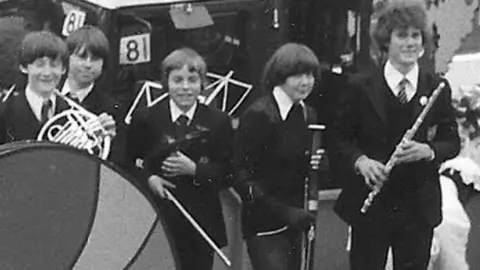 Labour party/PA Keir Starmer, in school uniform and holding a flute, stands alongside fellow school musicians