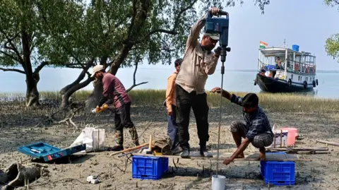 Sahadev Sharma Researchers drilling a hole in the ground