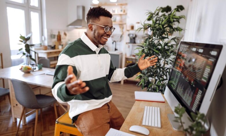 A person cheering while looking at graphs on a computer monitor.