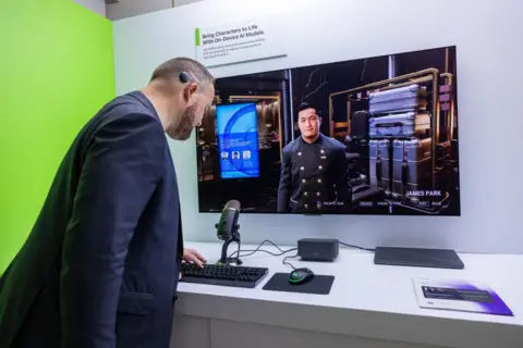 Getty Images A convention attendee stands in front of a screen displaying a CPU-controlled character in a 3D environment. The man in front of the screen is leaning over a keyboard. A sign above the screen reads 