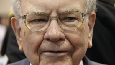 A pensive Warren Buffett surrounded by people at Berkshire Hathaway's annual shareholder meeting.