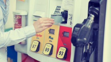 A hand placing a credit card into a gas pump card reader.