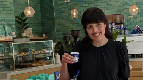 Zoe Corbyn Journalist Zoe Corbyn in a cafe holding a beanless coffee