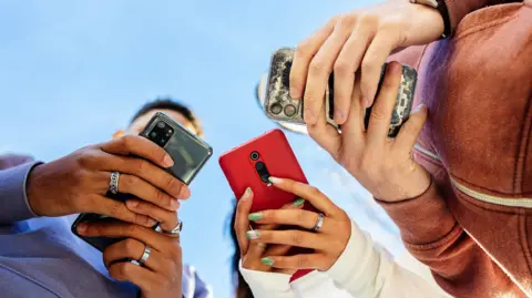 Getty Images Stock image of three young people using their smartphones