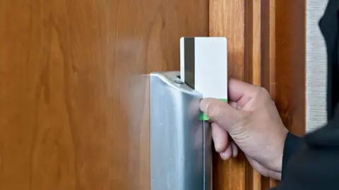 Getty Images A hand swiping a magnetic keycard through a door lock