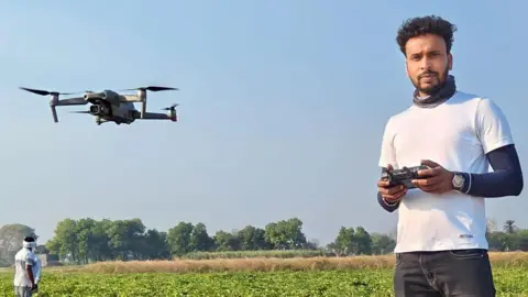 Vishal Jaiswal Vishal Jaiswal holding a drone controller, with a drone flying near him.