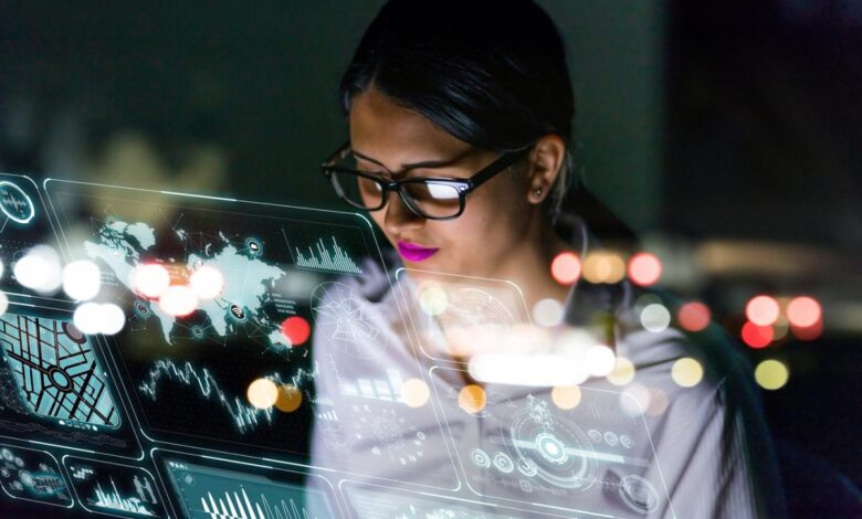 A person looking at graphs and charts on a futuristic see-through interface.