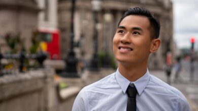 An investor smiles while standing outside and looking upward.