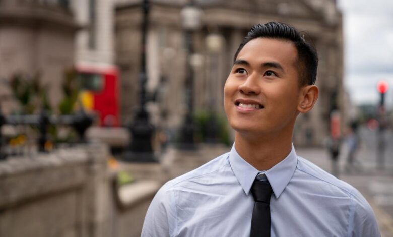 An investor smiles while standing outside and looking upward.