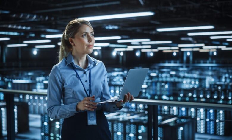 A person with a laptop surveying data center servers.