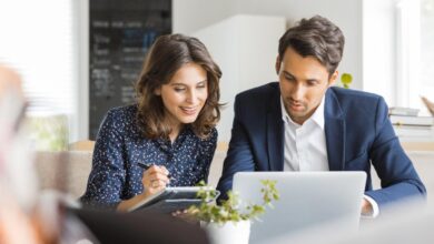 Two investors study something on a laptop.