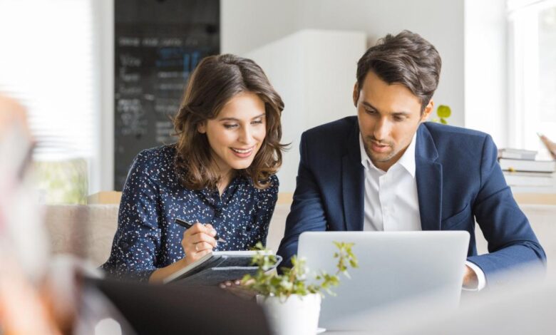 Two investors study something on a laptop.