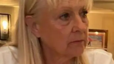 BBC Woman in her sixties with blonde hair in a white top