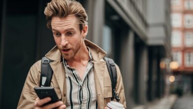 A surprised investor looking at a smartphone.