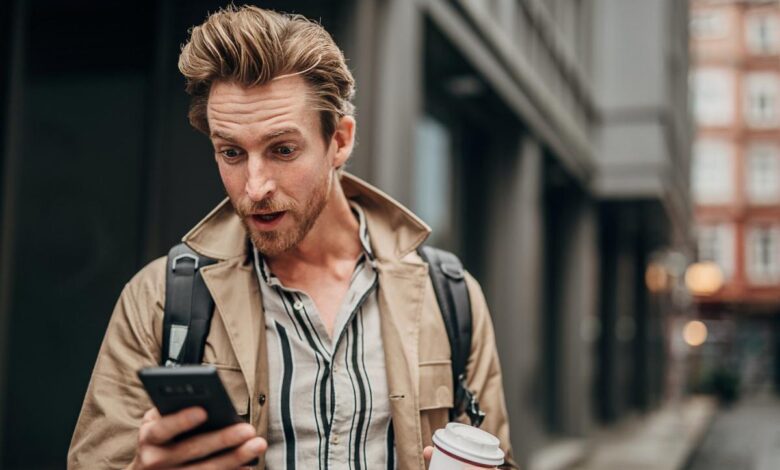 A surprised investor looking at a smartphone.