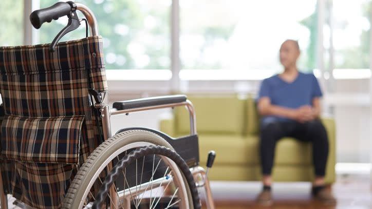 A nursing home resident sits on a couch   after getting out of his wheelchair.