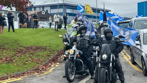 People on motorbikes which flags attached to them gather at Aberdeen airport