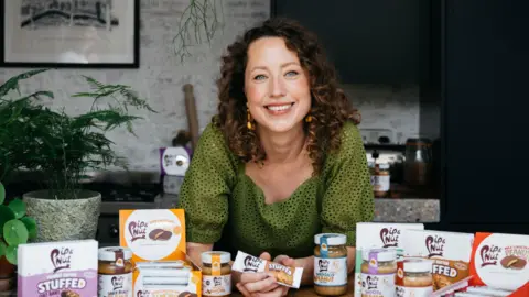 Pip Murray Pip Murray sitting down at a desk surrounded by her products