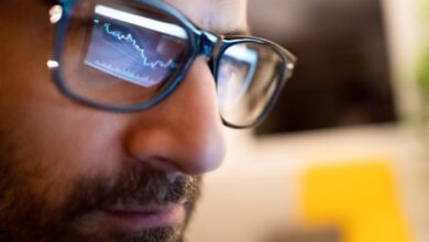 A stock chart from a computer monitor being reflected on the eyeglasses of a professional money manager.