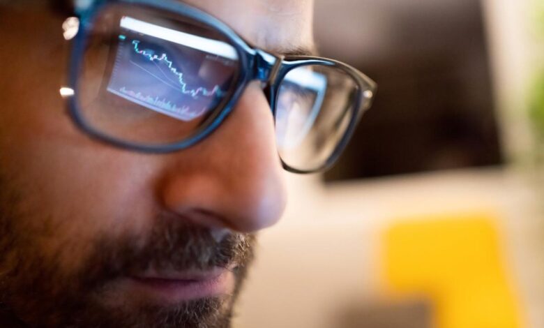 A stock chart from a computer monitor being reflected on the eyeglasses of a professional money manager.