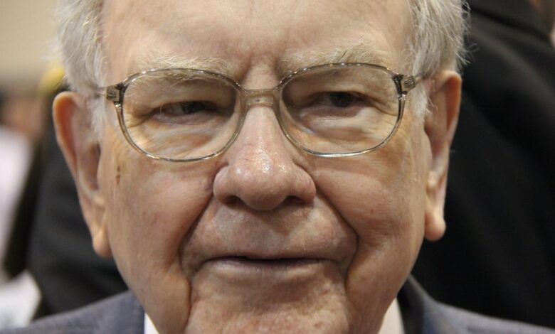 A pensive Warren Buffett surrounded by people at Berkshire Hathaway's annual shareholder meeting.