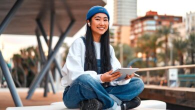 Some sitting on a chair while holding a tablet.