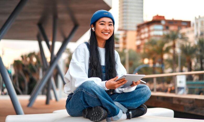 Some sitting on a chair while holding a tablet.