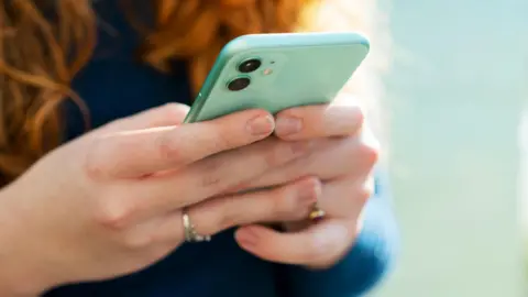 Getty Images A woman holding a mobile phone