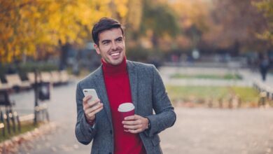 An investor smiles while walking through a park in the fall.