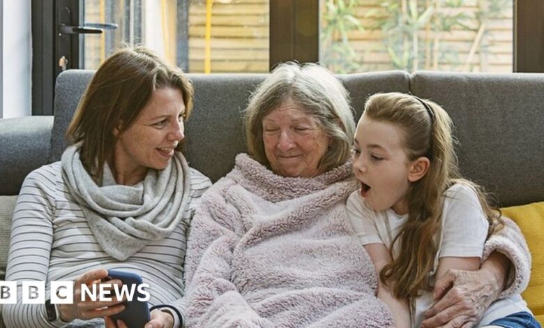 Mother, grandmother and daughter sitting on a sofa looking at a phone