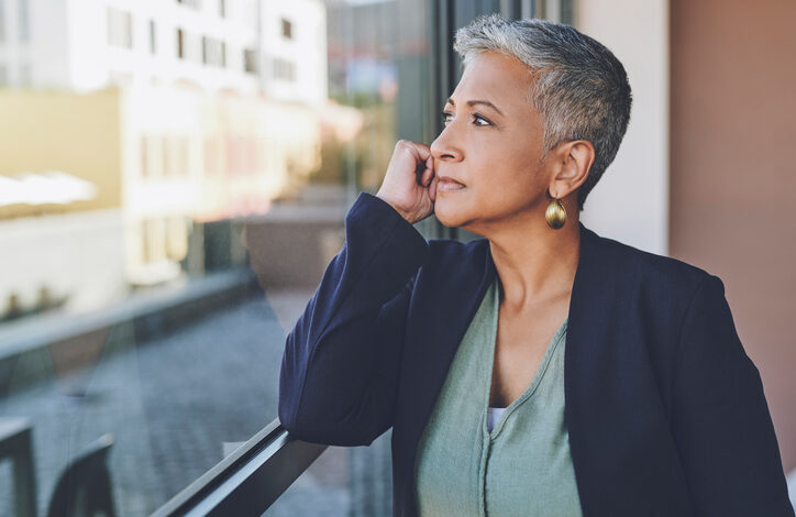 A woman looks out of the window in her office and contemplates whether she can afford to retire at 66.