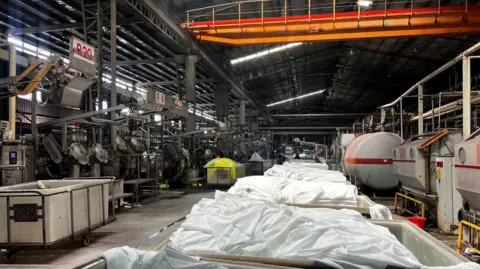 Crates of white textiles sit in a large dyeing factory