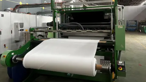 A roll of white cloth sits on Alchemie's new dyeing machine