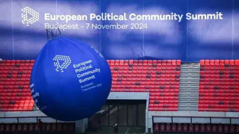 Reuters People put up a balloon sign at the European Political Community Summit venue, the Puskas Arena, in Budapest, Hungary, 7 November 2024