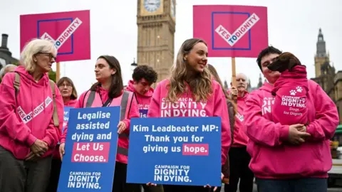 Getty Images Campaigners in favour of legalising assisted dying hold placards at a rally outside the Houses of Parliament 