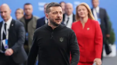 Getty Images Ukraine's president Volodymyr Zelensky wearing a black shirt with a Ukrainian trident motif arrives for a European summit in Hungary with dozens of other leaders