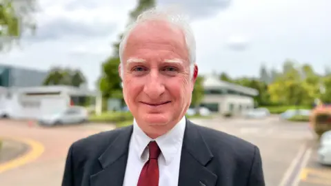 BBC/Martin Giles Farming minister Daniel Zeichner wearing a suit smiles for the camera  