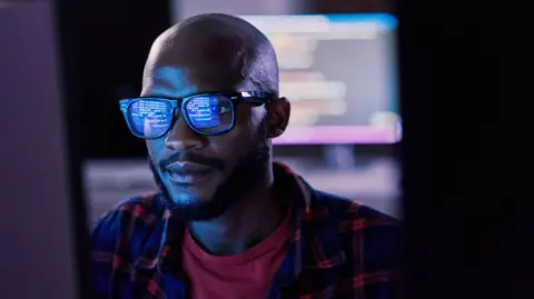 Getty Images A man looking at a computer screen, which is reflected in his glasses 