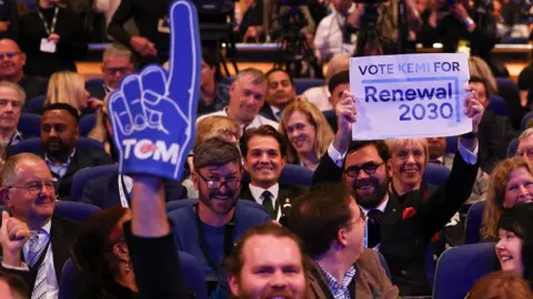 Getty Images Bearded man in the audience at the Conservative Party conference waves Tom Tugendhat foam finger