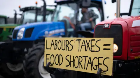 Getty Images Farmers stage a protest in front of Venue Cymru against a rise in inheritance tax in Llandudno, Wales. A placard on the front of a red tractor reads 