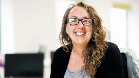 Energy Systems Catapult Jo Atkinson looking happy and sitting at her desk