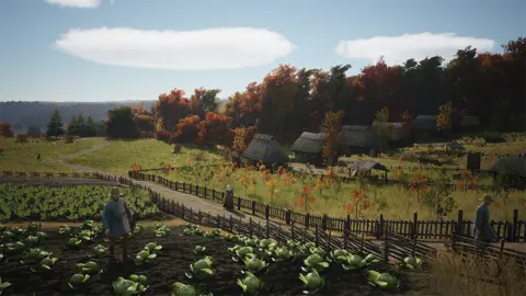 Slavic Magic Screenshot shows a pastoral scene depicting a middle ages settlement. In the foreground a farm worker tends to crops arranged in rows. Further back, trees sit in a fenced area and a path leads to a row of small, thatched dwellings. Other workers dressed in period clothing mill about the landscape, which stretches off into the distance.