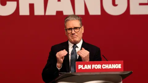 Reuters Sir Keir Starmer giving a speech on Thursday, standing behind a lectern with the motto 'Plan for change' on it. He is gesturing with his hands.