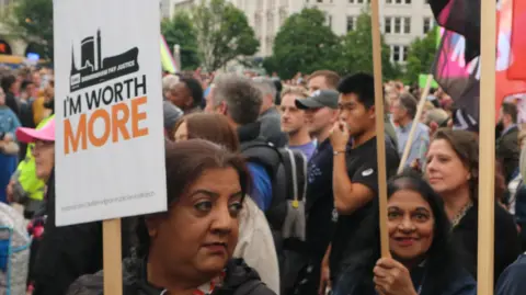 Several women holding placards with one visible saying 