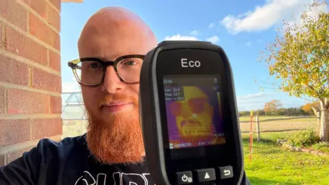 Jamie Matthews  Jamie Matthews, with a big red beard, holds up a thermal imaging device