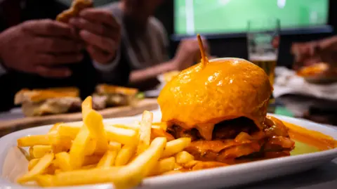 Getty Images A plate of burger and chips in front of a TV screen